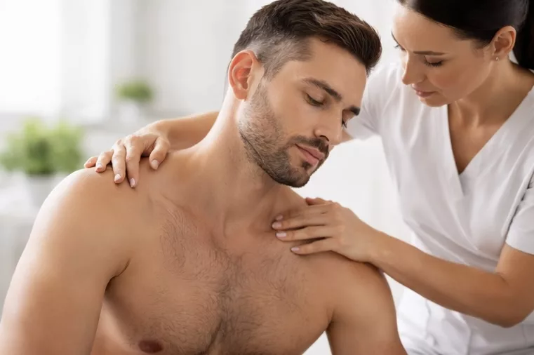 Osteopath performing neck adjustment on male patient to reduce stiffness and improve range of motion